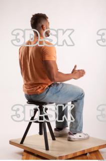 Sitting pose orange thsirt light blue jeans of bodybuilder Harold…